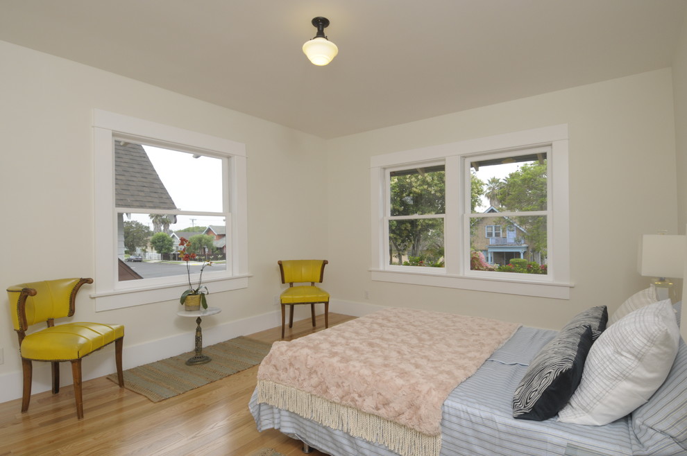 Large arts and crafts guest bedroom in Los Angeles with white walls and light hardwood floors.
