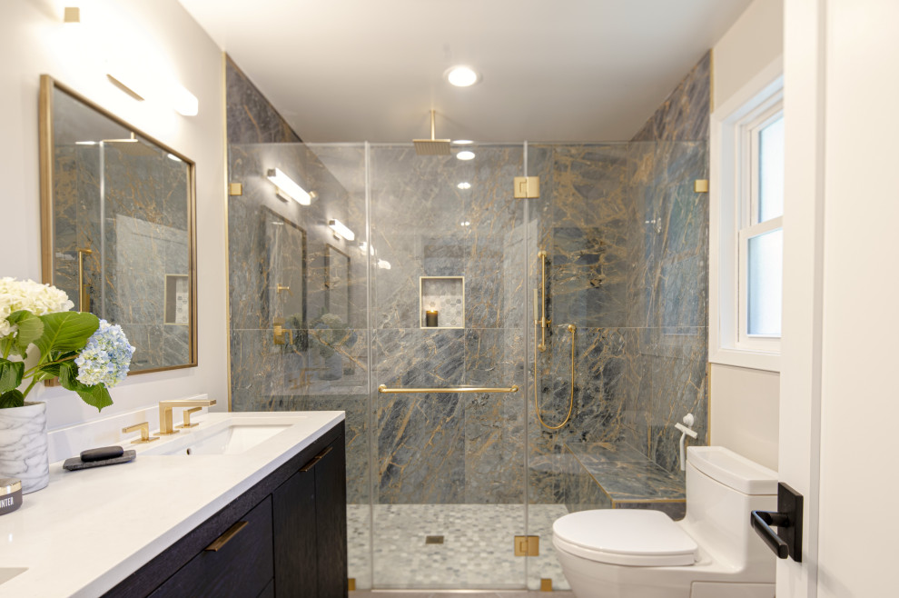 Large modern ensuite bathroom in San Francisco with raised-panel cabinets, brown cabinets, a double shower, a two-piece toilet, blue tiles, marble tiles, white walls, porcelain flooring, a submerged sink, solid surface worktops, grey floors, a hinged door, white worktops, a shower bench, double sinks and a freestanding vanity unit.