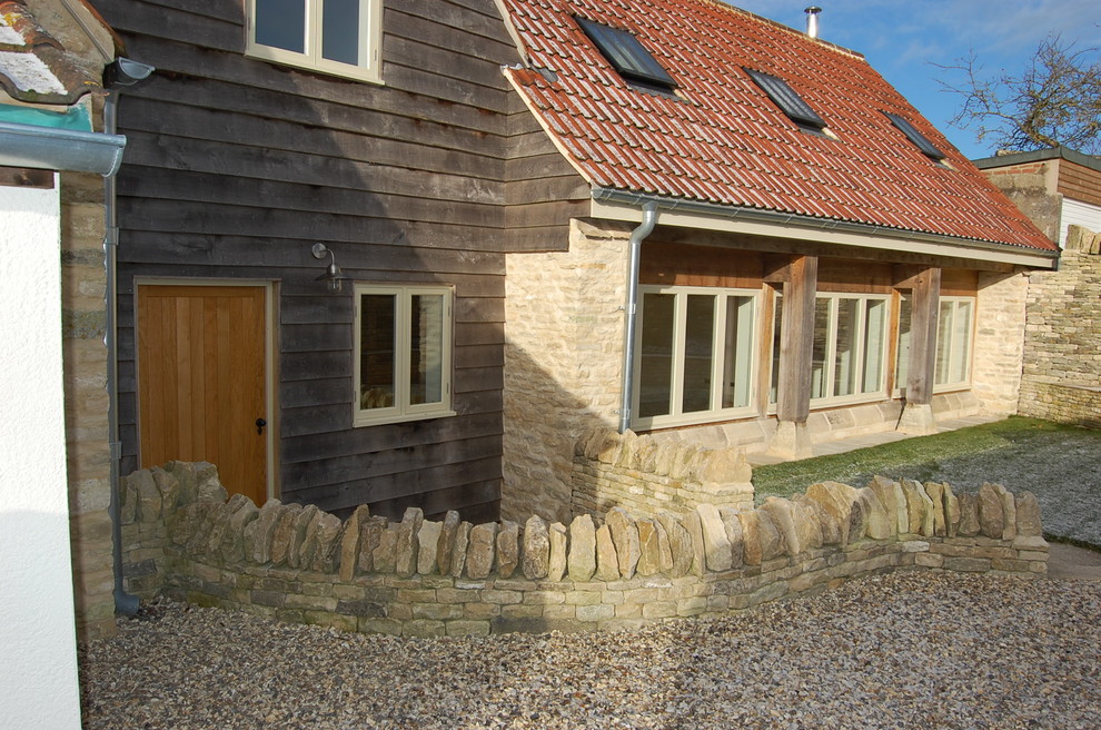 This is an example of a large country two-storey beige exterior in Gloucestershire with stone veneer and a gable roof.