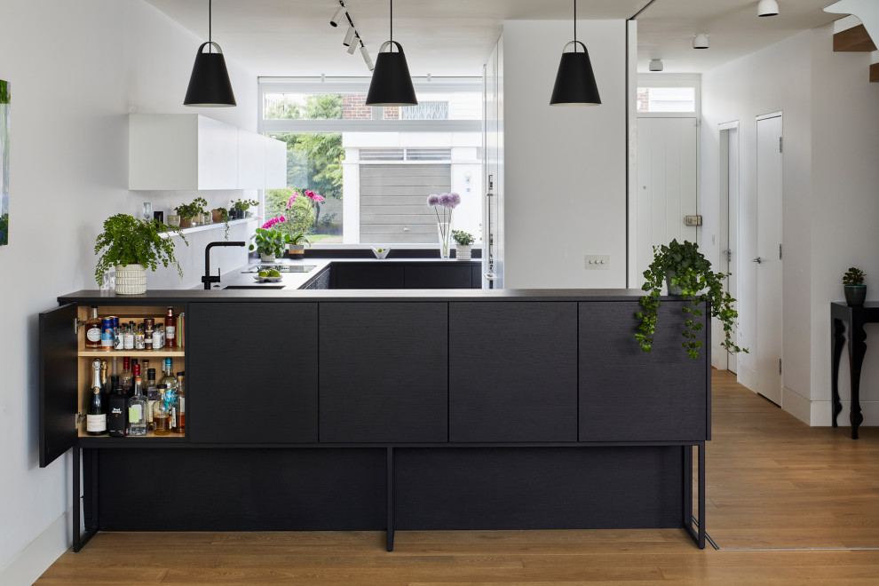 Foto di una cucina minimalista di medie dimensioni con ante lisce, ante nere, top in legno, paraspruzzi grigio e top nero