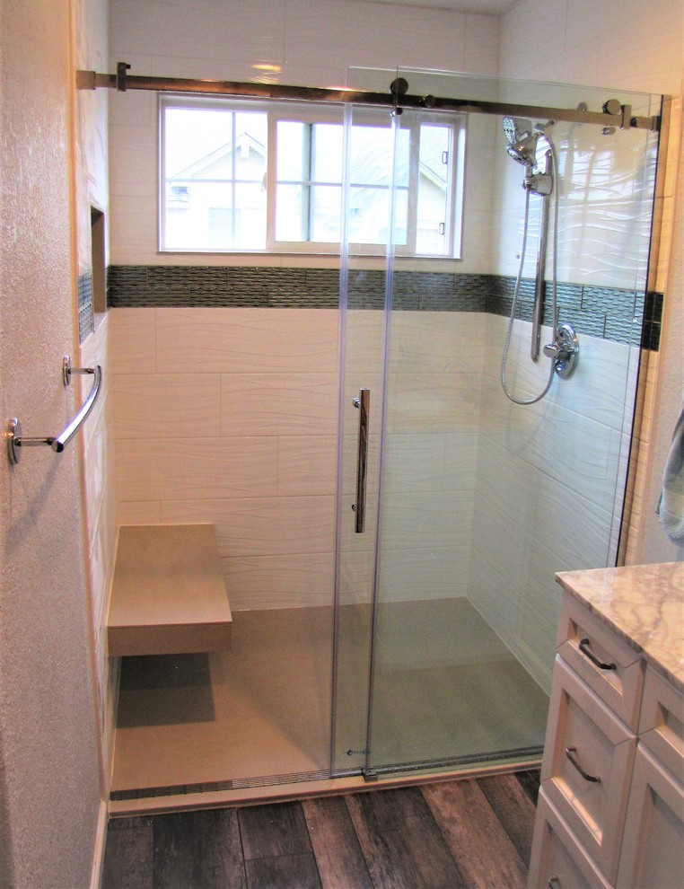 Mid-sized modern master bathroom in Denver with raised-panel cabinets, white cabinets, a curbless shower, white tile, porcelain tile, grey walls, vinyl floors, an undermount sink, marble benchtops, brown floor, a sliding shower screen and beige benchtops.