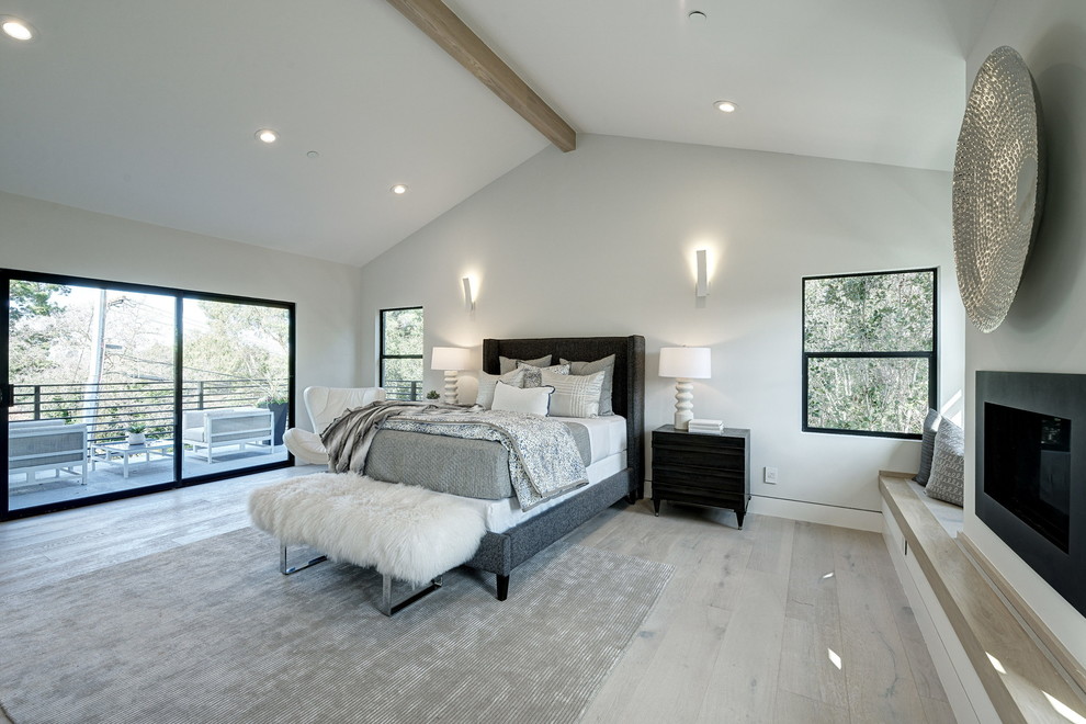 Inspiration for a large transitional master bedroom in San Francisco with white walls, light hardwood floors, a ribbon fireplace, a metal fireplace surround and grey floor.