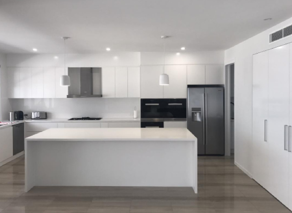 Design ideas for a large modern l-shaped kitchen pantry in Brisbane with an undermount sink, flat-panel cabinets, white cabinets, quartz benchtops, white splashback, glass sheet splashback, stainless steel appliances, with island, marble floors and green floor.