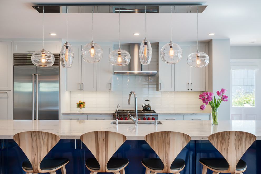 This is an example of a transitional galley kitchen in San Francisco with an undermount sink, shaker cabinets, white cabinets, white splashback, subway tile splashback, stainless steel appliances, medium hardwood floors and with island.