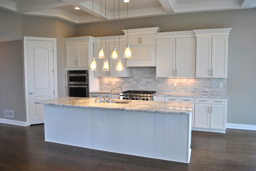 Eat-in kitchen - transitional medium tone wood floor eat-in kitchen idea in Columbus with flat-panel cabinets, white cabinets, granite countertops, gray backsplash, stone tile backsplash, stainless steel appliances and an island
