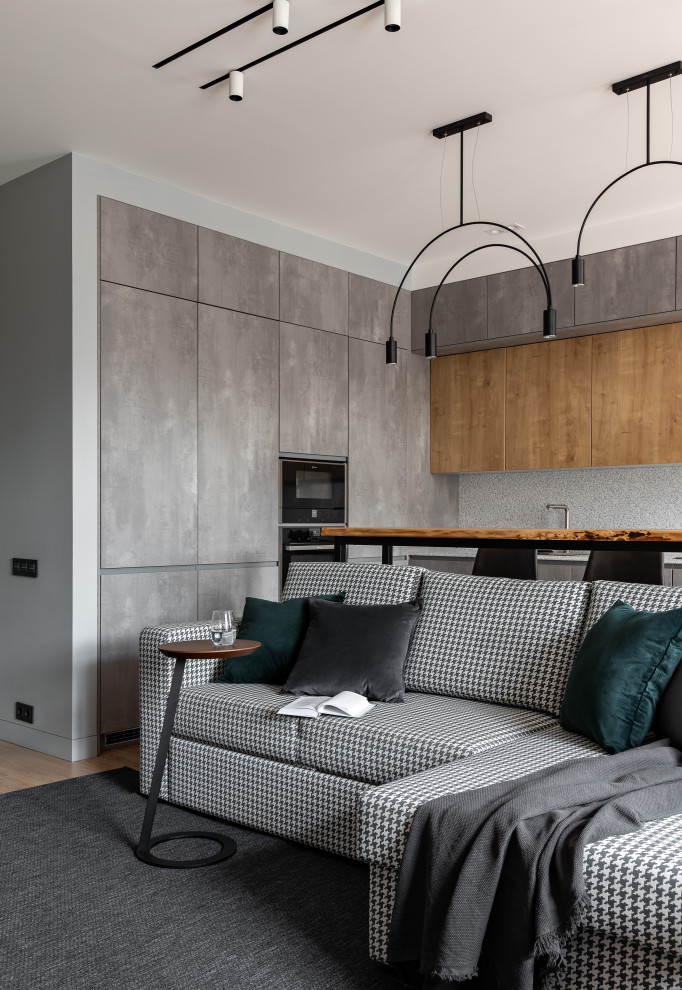 Источник вдохновения для домашнего уюта: гостиная комната среднего размера в современном стиле с серыми стенами, паркетным полом среднего тона, телевизором на стене, коричневым полом и акцентной стеной
