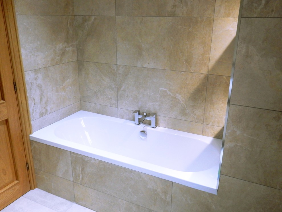 This is an example of a small contemporary kids bathroom in Dublin with a drop-in tub, beige tile, porcelain tile, beige walls, porcelain floors and beige floor.