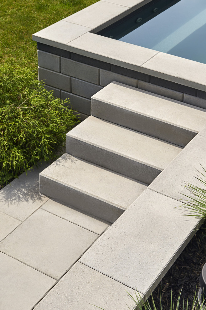 Photo of a modern backyard garden in Montreal with a retaining wall and concrete pavers.