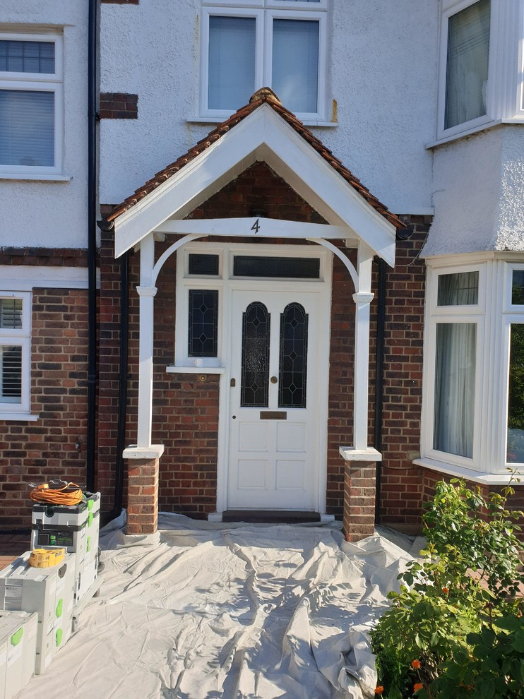 This is an example of a mid-sized traditional front door in London with red walls, concrete floors, a single front door, a white front door, grey floor, recessed and brick walls.