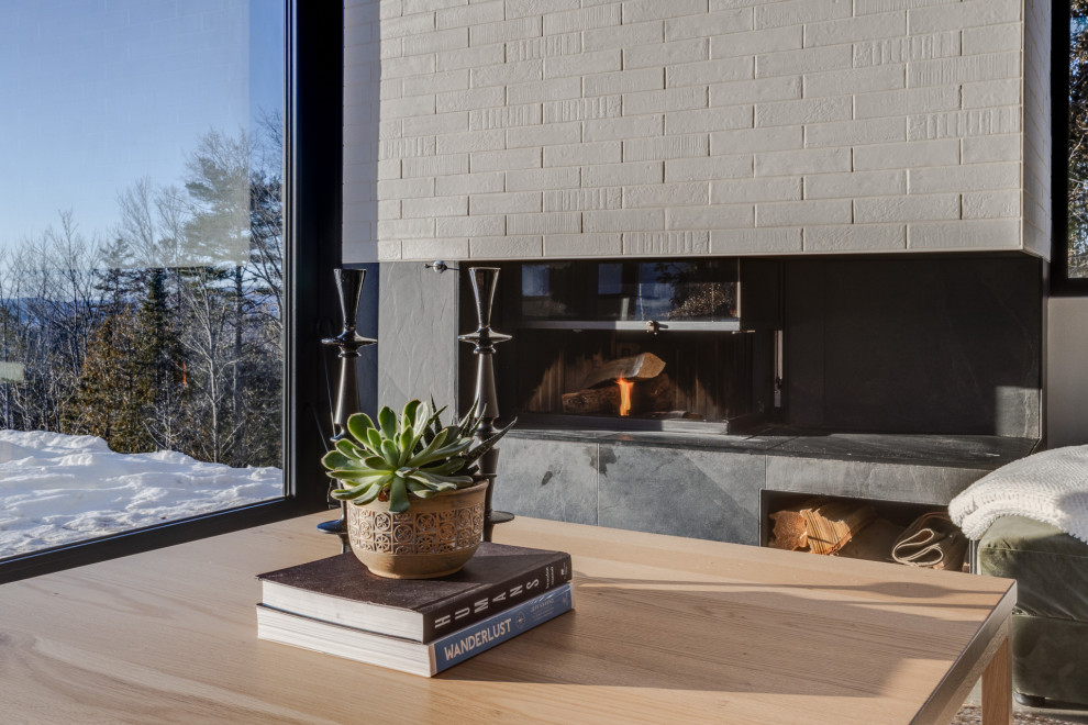This is an example of a scandinavian open plan living room in Montreal with concrete flooring, a corner fireplace, a tiled fireplace surround, grey floors and a wood ceiling.
