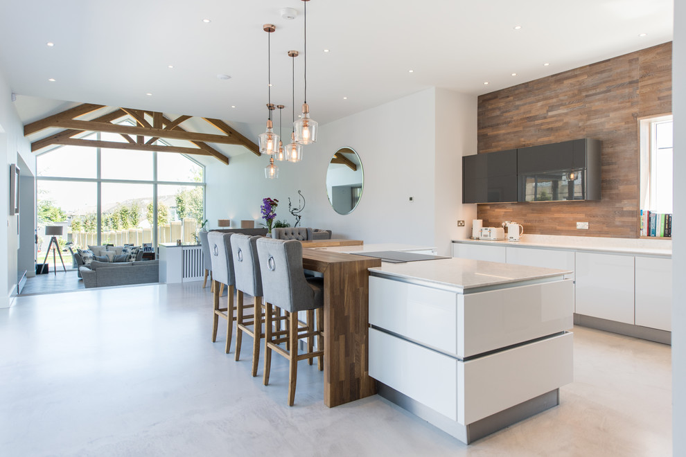 Design ideas for a large country open plan kitchen in Dublin with flat-panel cabinets, brown splashback, timber splashback, concrete floors, with island, grey floor, white cabinets and panelled appliances.