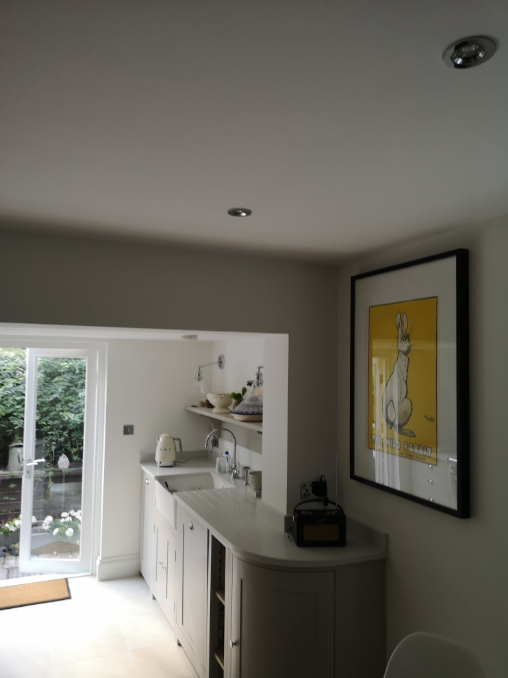 Design ideas for a mid-sized traditional single-wall eat-in kitchen in London with a farmhouse sink, shaker cabinets, grey cabinets, marble benchtops, beige splashback, ceramic splashback, stainless steel appliances, ceramic floors, no island, beige floor and white benchtop.