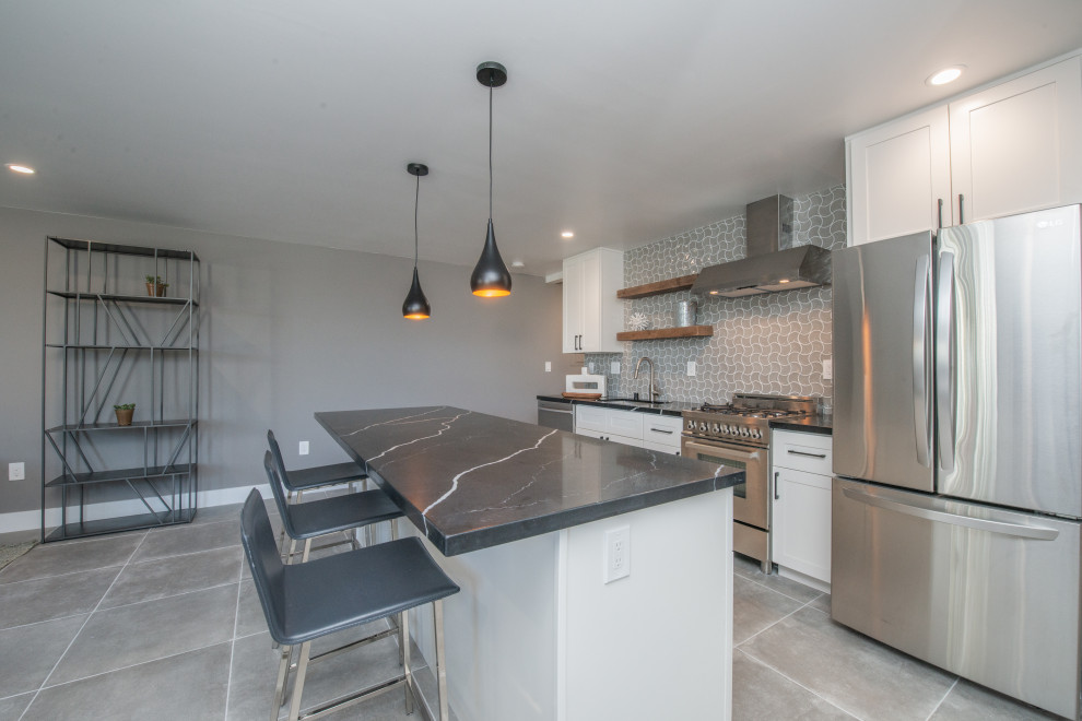 Small traditional galley open plan kitchen in Los Angeles with an undermount sink, shaker cabinets, white cabinets, quartz benchtops, grey splashback, porcelain splashback, stainless steel appliances, cement tiles, with island, grey floor and black benchtop.