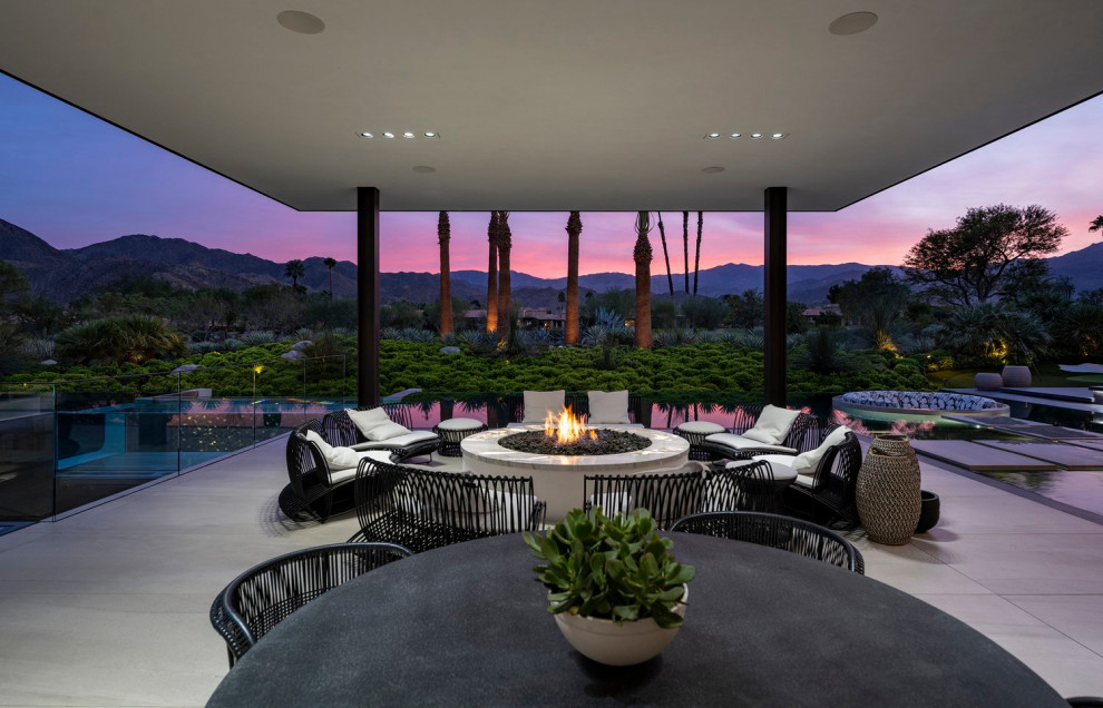 Inspiration for an expansive modern back patio in Los Angeles with a fire feature and an awning.