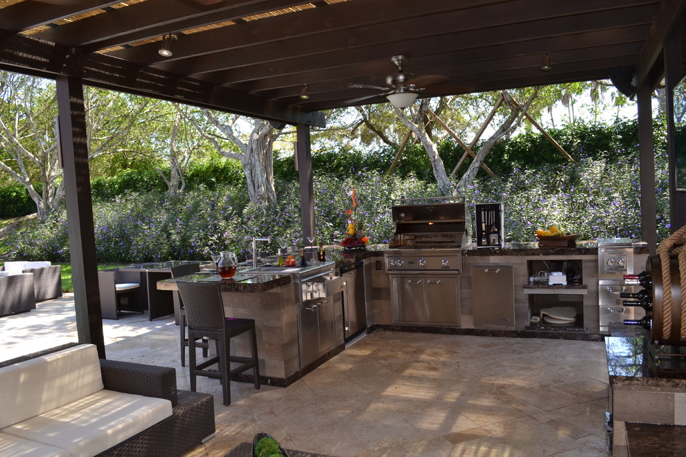 Design ideas for an expansive traditional backyard patio in Miami with an outdoor kitchen, natural stone pavers and a pergola.
