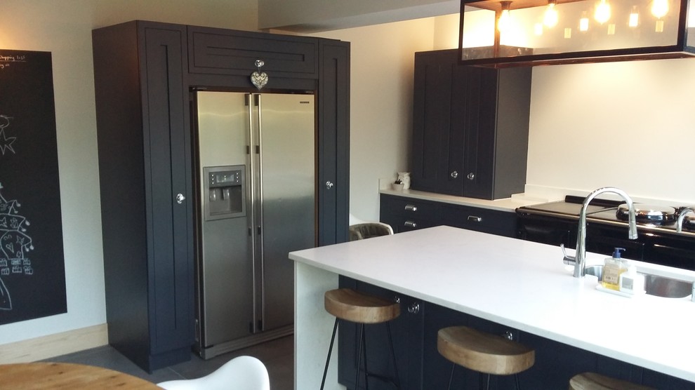 Contemporary kitchen in Cheshire with a submerged sink, composite countertops, white splashback, stone slab splashback, stainless steel appliances, porcelain flooring and an island.