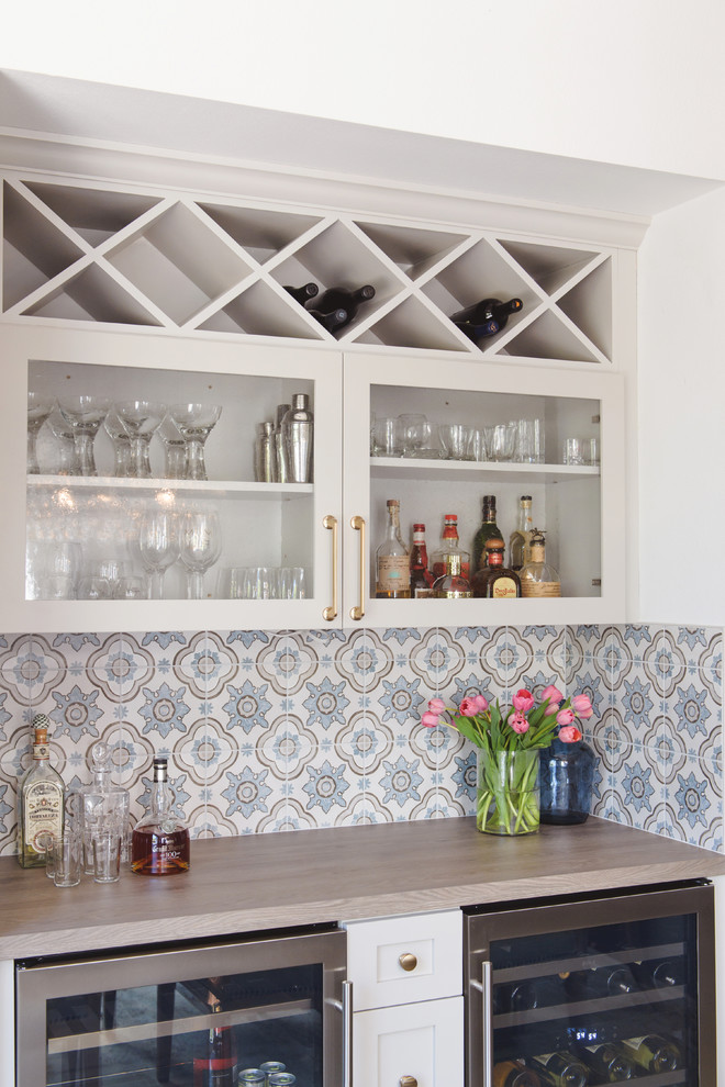 Photo of a mid-sized contemporary galley home bar in San Diego with glass-front cabinets, white cabinets, wood benchtops, multi-coloured splashback and ceramic splashback.