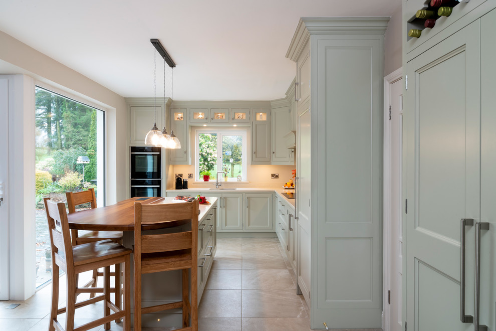 Inspiration for a mid-sized country eat-in kitchen in Cork with a double-bowl sink, flat-panel cabinets, green cabinets, quartzite benchtops, beige splashback, stainless steel appliances, ceramic floors, with island, beige floor and beige benchtop.