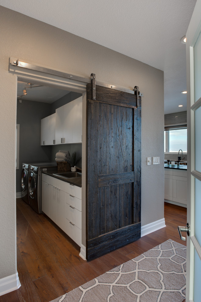 Home design - large transitional galley medium tone wood floor home design idea in Denver with a drop-in sink, flat-panel cabinets, white cabinets, quartz countertops, gray walls and a side-by-side washer/dryer