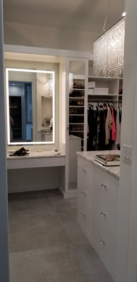 Photo of a large modern gender-neutral walk-in wardrobe with flat-panel cabinets, white cabinets, porcelain floors and grey floor.