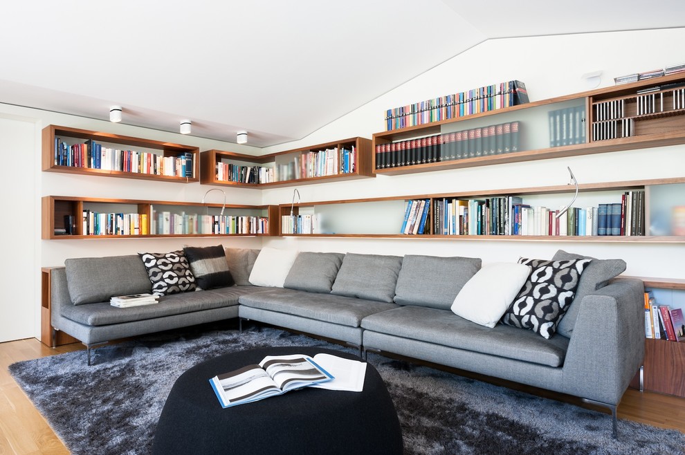 Design ideas for a large modern family room in Munich with a library, white walls and medium hardwood floors.