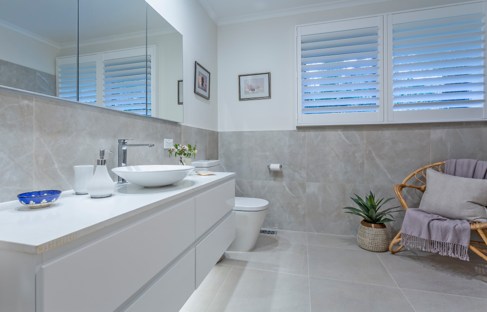 Idée de décoration pour une grande salle de bain design avec un placard à porte plane, des portes de placard blanches, un carrelage gris, un mur blanc, une vasque, un sol gris, un plan de toilette blanc, meuble simple vasque et meuble-lavabo suspendu.