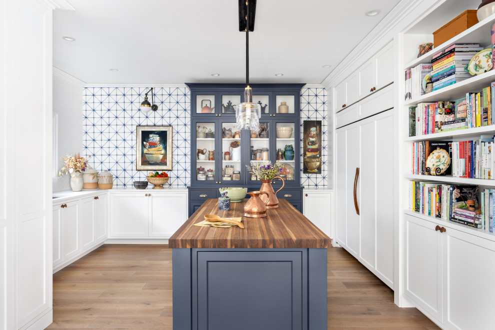 Photo of an expansive nautical u-shaped kitchen pantry in Other with medium hardwood flooring, brown floors, a submerged sink, shaker cabinets, white cabinets, wood worktops, integrated appliances, an island, brown worktops, white splashback and porcelain splashback.