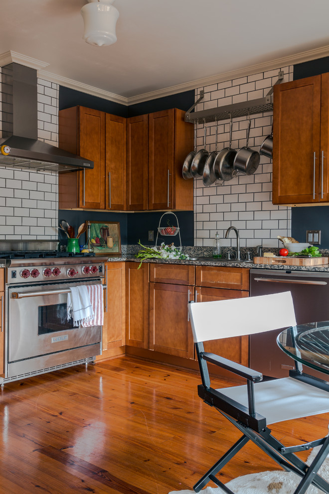 This is an example of a mid-sized traditional l-shaped eat-in kitchen in New Orleans with shaker cabinets, stainless steel appliances, subway tile splashback, medium wood cabinets, white splashback, a double-bowl sink, granite benchtops, medium hardwood floors and no island.