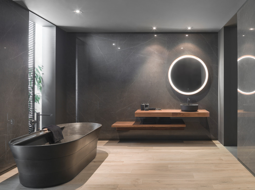 This is an example of a modern master bathroom in Other with a freestanding tub, black walls, light hardwood floors, a vessel sink, beige floor, open cabinets, medium wood cabinets, wood benchtops and brown benchtops.