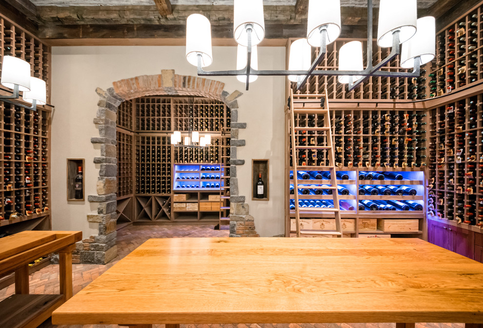 This is an example of an expansive country wine cellar in New York with brick floors, storage racks and red floor.
