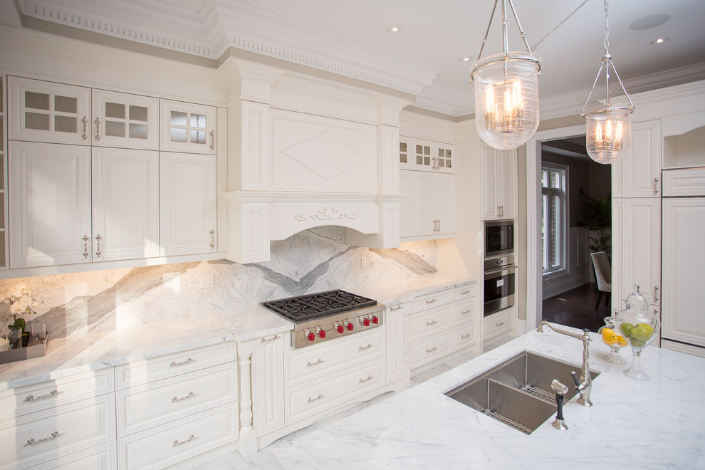 This is an example of a large contemporary galley kitchen in Toronto with an undermount sink, raised-panel cabinets, white cabinets, granite benchtops, stainless steel appliances and with island.