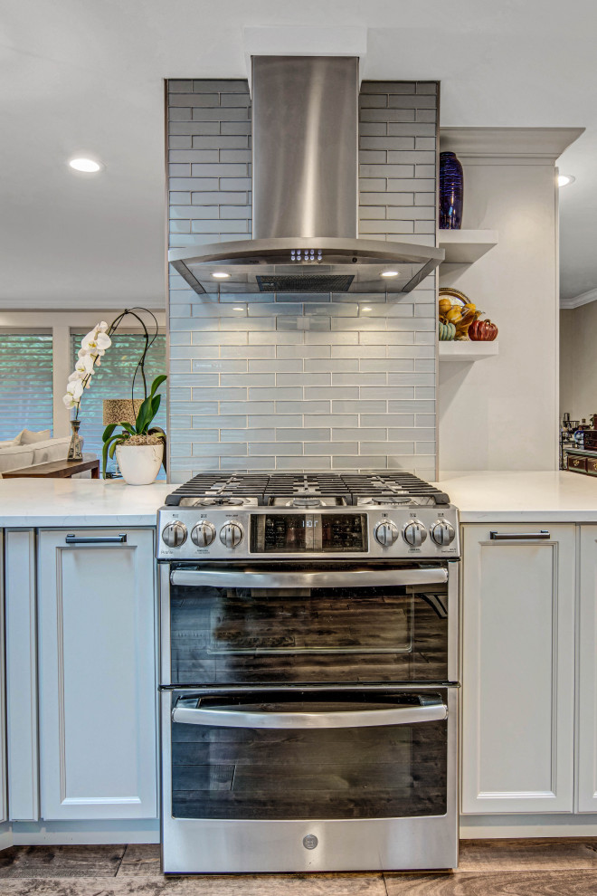 Inspiration for a transitional medium tone wood floor and brown floor open concept kitchen remodel in Seattle with an undermount sink, recessed-panel cabinets, gray cabinets, quartz countertops, gray backsplash, subway tile backsplash, stainless steel appliances and white countertops