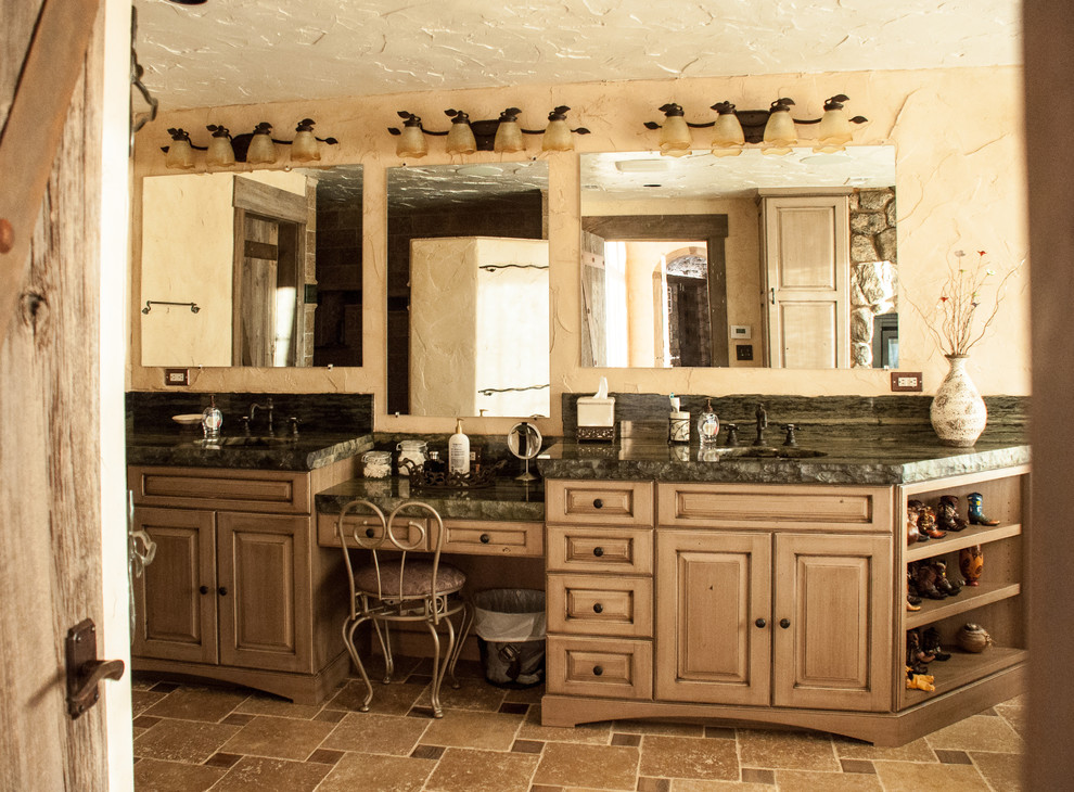 This is an example of a large country master bathroom in Denver with furniture-like cabinets, beige cabinets, beige tile, limestone, limestone floors, an undermount sink and granite benchtops.