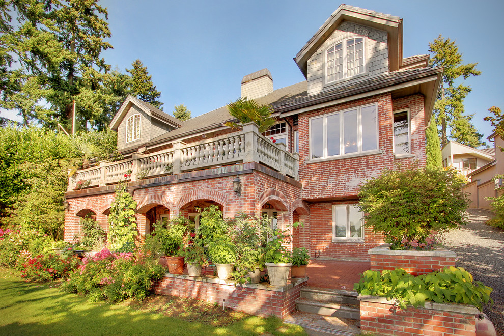 Photo of an expansive traditional two-storey brick red house exterior in Seattle with a gable roof and a shingle roof.