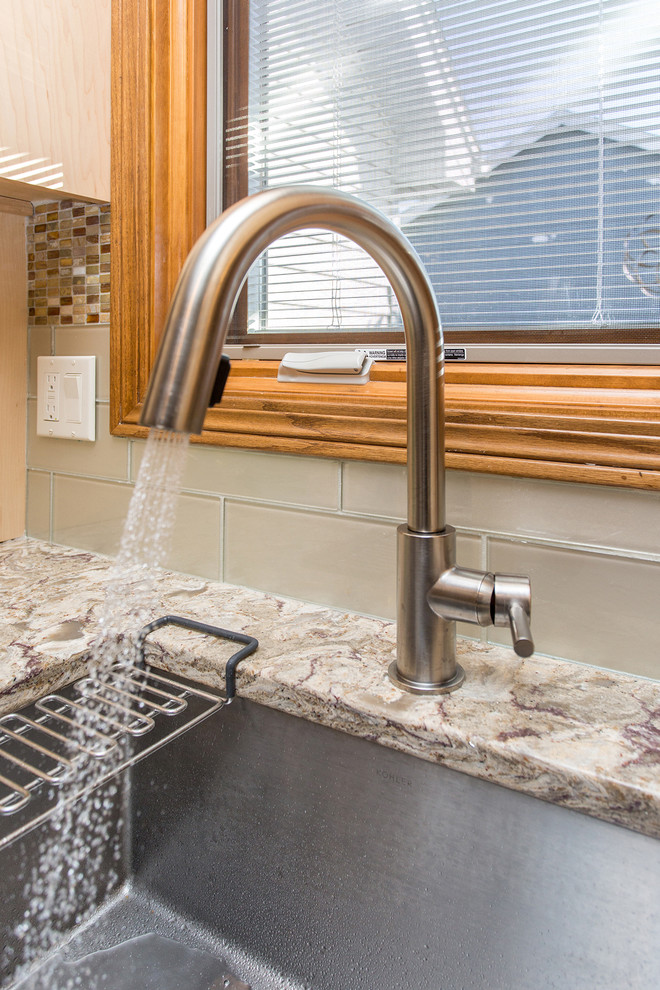 Open concept kitchen - mid-sized transitional l-shaped porcelain tile open concept kitchen idea with an undermount sink, flat-panel cabinets, light wood cabinets, beige backsplash, stainless steel appliances, an island, quartz countertops and porcelain backsplash