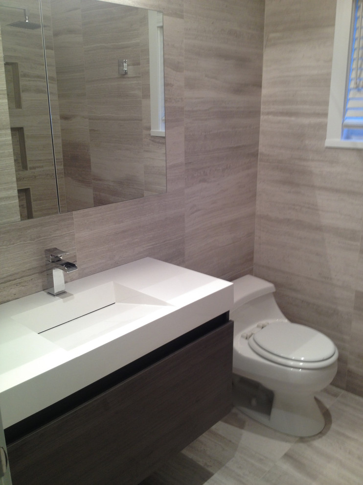This is an example of a contemporary 3/4 bathroom in Toronto with flat-panel cabinets, dark wood cabinets, a one-piece toilet, gray tile, porcelain tile, grey walls, porcelain floors, an integrated sink and solid surface benchtops.