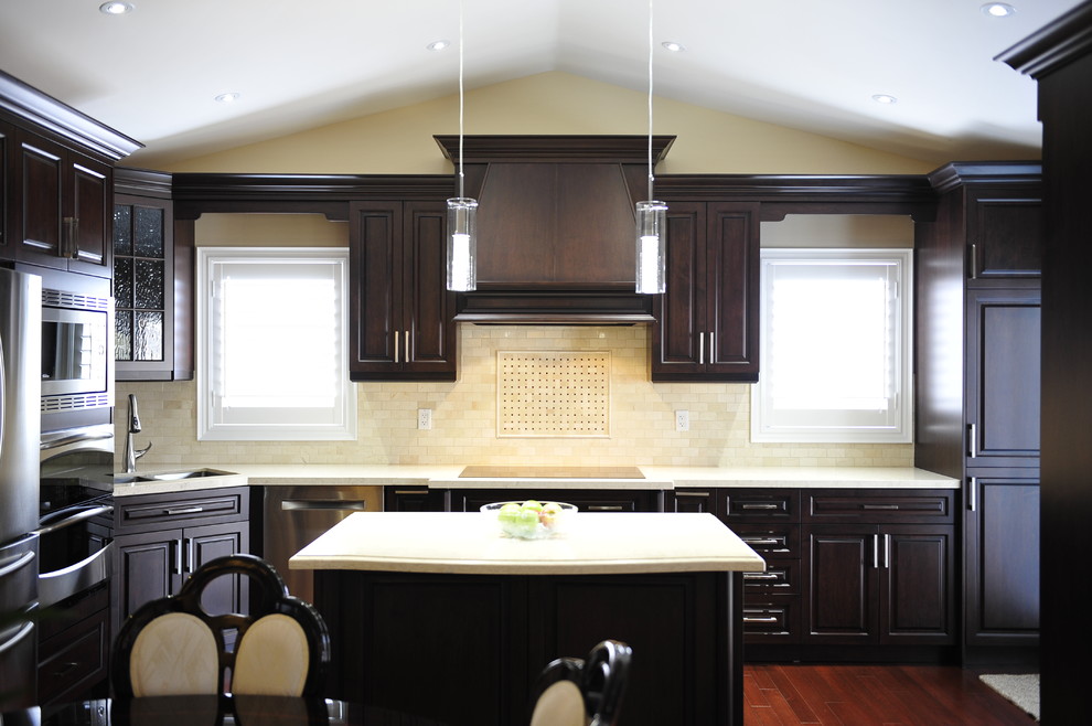 Example of a mid-sized transitional u-shaped eat-in kitchen design in Toronto with a double-bowl sink, raised-panel cabinets, dark wood cabinets, quartz countertops, multicolored backsplash, matchstick tile backsplash, stainless steel appliances and a peninsula