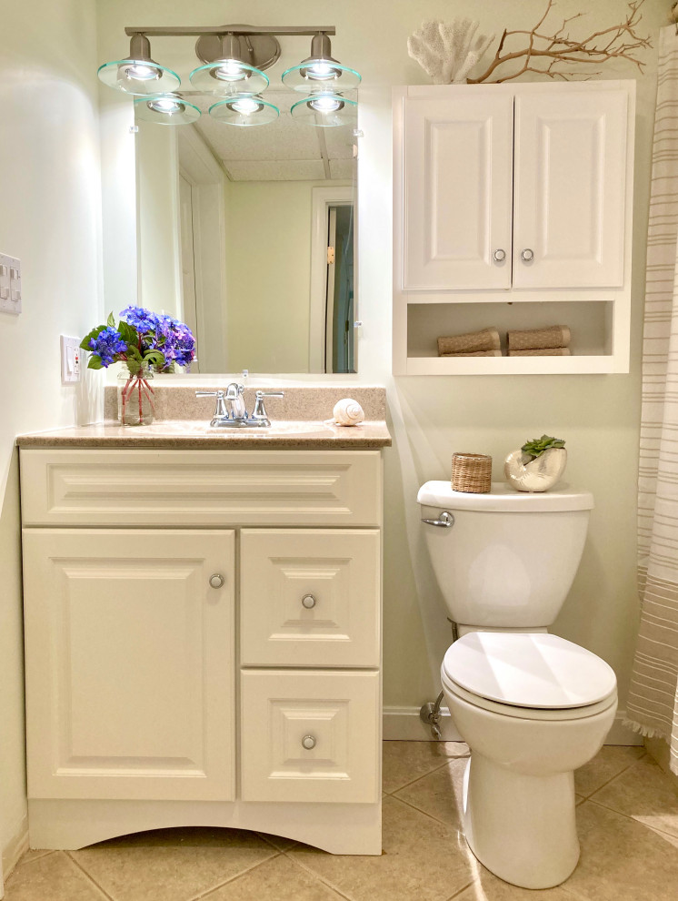 Aménagement d'une salle de bain beige et blanche bord de mer de taille moyenne avec un placard en trompe-l'oeil, des portes de placard blanches, une baignoire en alcôve, WC séparés, un carrelage beige, un mur beige, un sol en carrelage de porcelaine, un lavabo encastré, un plan de toilette en surface solide, un sol beige, un plan de toilette beige, meuble simple vasque et meuble-lavabo sur pied.