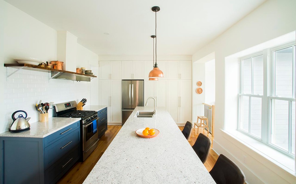 Inspiration for a mid-sized transitional galley medium tone wood floor eat-in kitchen remodel in Toronto with an undermount sink, shaker cabinets, blue cabinets, quartzite countertops, white backsplash, ceramic backsplash, stainless steel appliances and an island