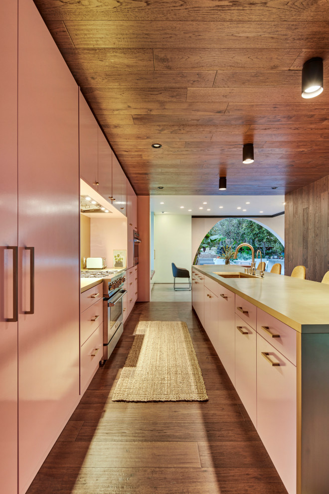 Large mediterranean single-wall open plan kitchen in Los Angeles with a submerged sink, flat-panel cabinets, pink cabinets, yellow splashback, metal splashback, stainless steel appliances, dark hardwood flooring, an island, yellow worktops, a wood ceiling and brown floors.