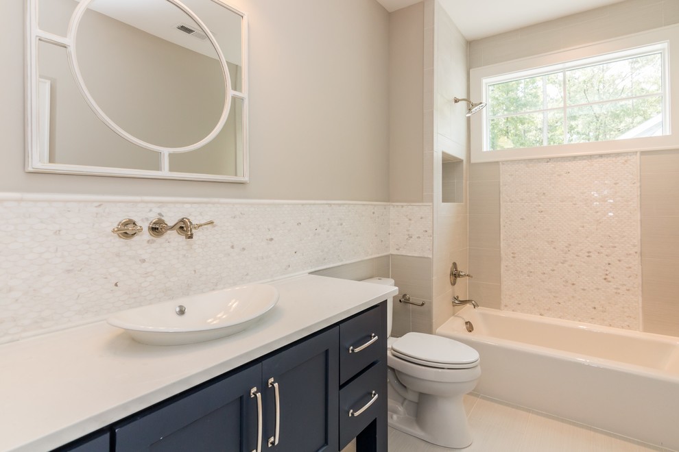 Photo of a large country bathroom in Raleigh with furniture-like cabinets, blue cabinets, an alcove tub, a shower/bathtub combo, a two-piece toilet, gray tile, porcelain tile, grey walls, ceramic floors, a drop-in sink and quartzite benchtops.