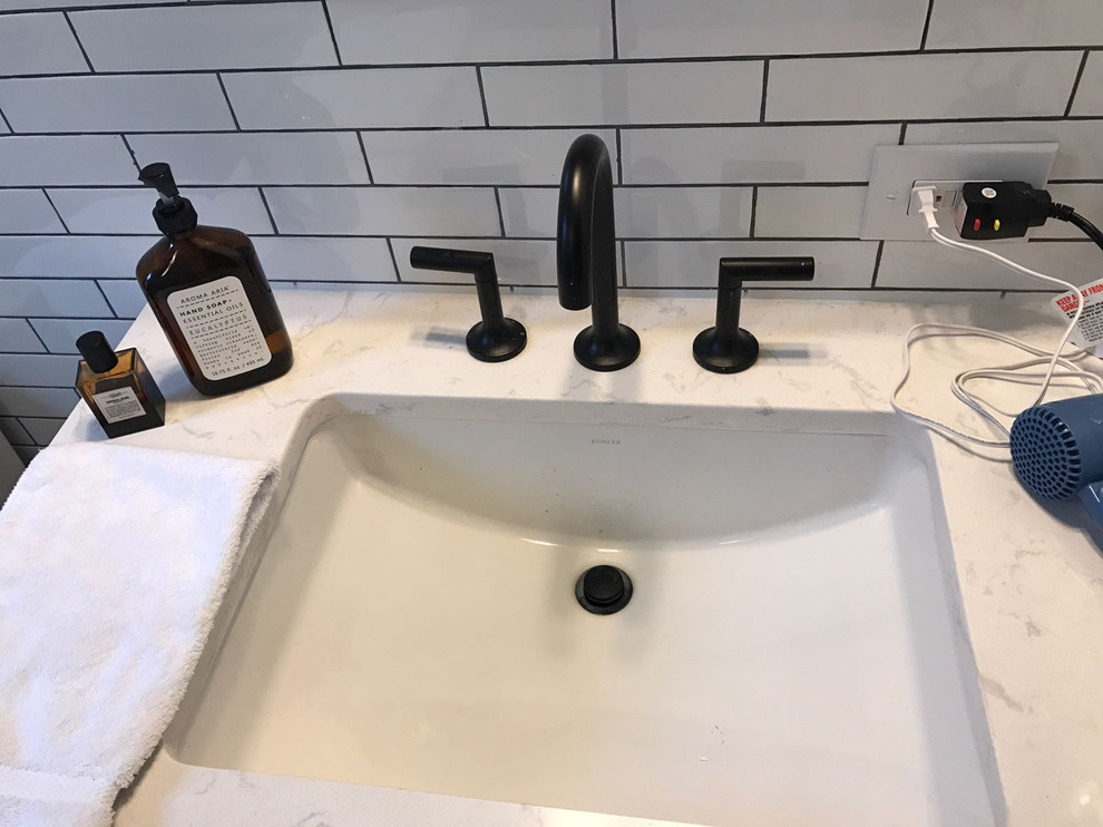 Mid-sized contemporary 3/4 bathroom in DC Metro with shaker cabinets, black cabinets, an alcove tub, a shower/bathtub combo, a one-piece toilet, white tile, subway tile, white walls, marble floors, an undermount sink, marble benchtops, multi-coloured floor, a hinged shower door and white benchtops.
