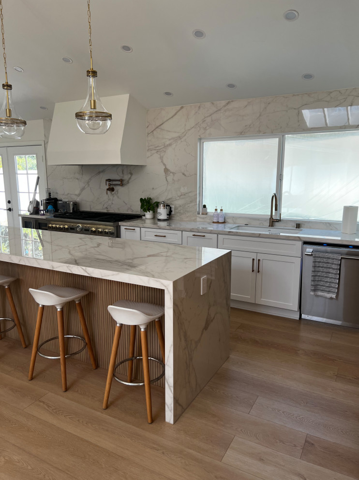 This is an example of a farmhouse galley kitchen in San Diego with shaker cabinets, composite countertops, stone slab splashback, stainless steel appliances and an island.
