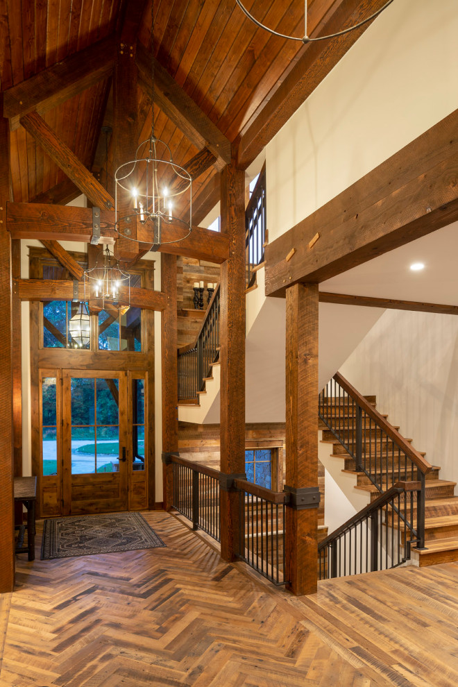Inspiration for an expansive country foyer in Minneapolis with beige walls, ceramic floors, a single front door, a medium wood front door, grey floor and exposed beam.