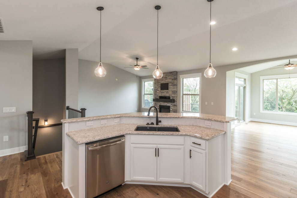 Inspiration for a large transitional u-shaped brown floor and light wood floor kitchen remodel with an undermount sink, shaker cabinets, white cabinets, quartz countertops, white backsplash, glass tile backsplash, stainless steel appliances, an island and multicolored countertops