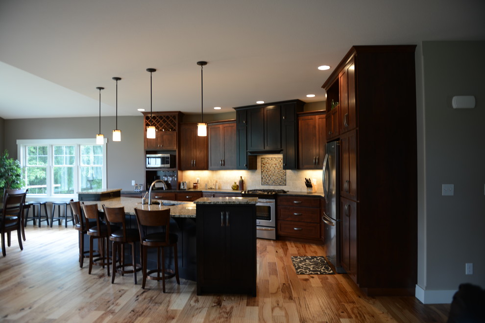 Design ideas for a large arts and crafts open plan kitchen in Chicago with an undermount sink, shaker cabinets, medium wood cabinets, laminate benchtops, beige splashback, stainless steel appliances, medium hardwood floors and with island.