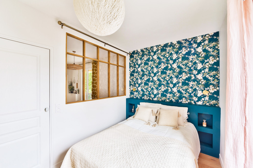 This is an example of a mid-sized scandinavian bedroom in Paris with blue walls, light hardwood floors, no fireplace and wallpaper.