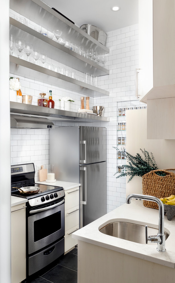 Inspiration for a small contemporary galley kitchen in New York with an undermount sink, open cabinets, stainless steel cabinets, white splashback, subway tile splashback and black floor.