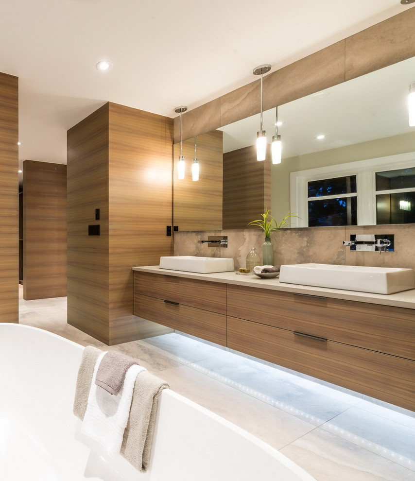 Large contemporary master bathroom in Vancouver with flat-panel cabinets, light wood cabinets, a freestanding tub, beige tile, stone tile, marble floors, a vessel sink and solid surface benchtops.