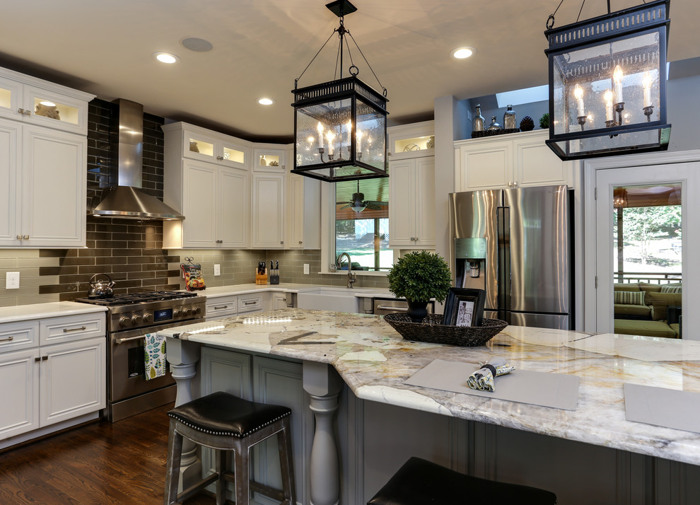 Large transitional l-shaped dark wood floor and brown floor eat-in kitchen photo in Raleigh with a farmhouse sink, recessed-panel cabinets, white cabinets, quartzite countertops, gray backsplash, glass tile backsplash, stainless steel appliances and an island